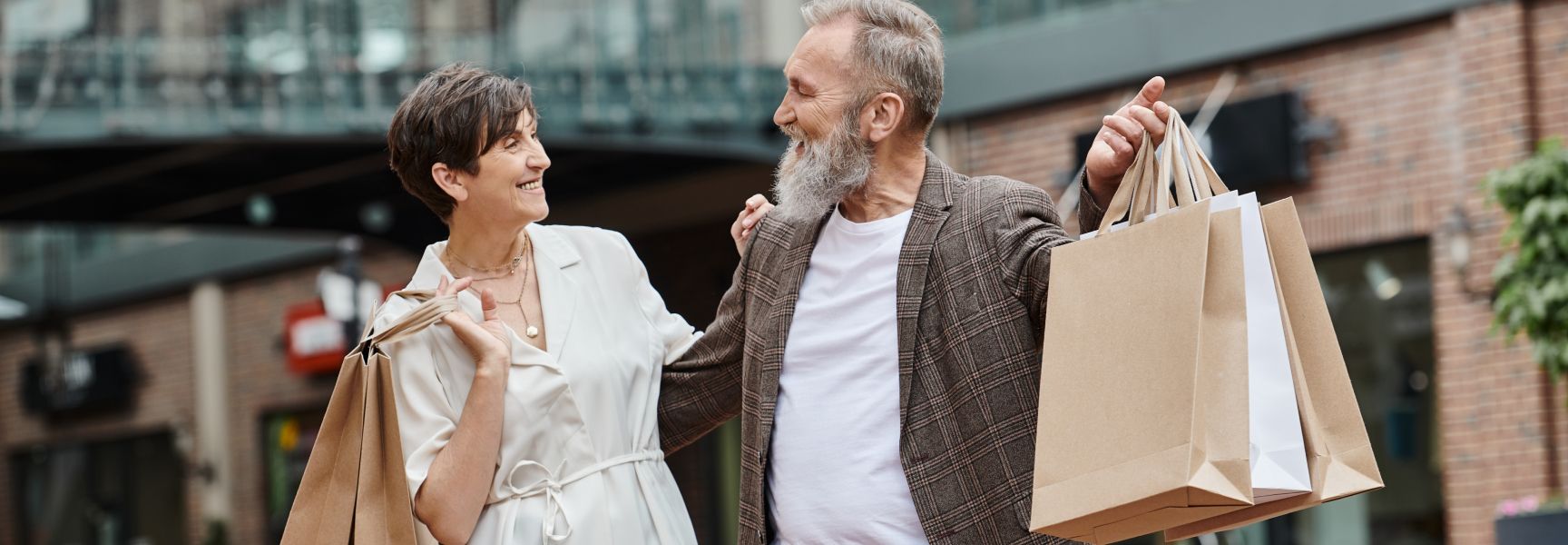 Ein Ehepaar beim shoppen mit mehreren Tüten in den Händen. Sie schauen sich glücklich an